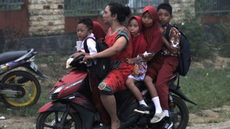 Ibu-ibu yang mengantar anak ke sekolah nanti jangan seperti ibu ini. Gambar: BBC.com