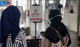 Dua orang penumpang sedang mengunduh aplikasi Peduli Lindungi di stasiun Pasar Minggu (Foto Setiyo)