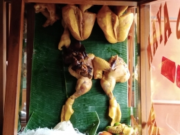 Papan kayu beralas daun pisang yang ditancapkan ayam bumbu kuning, sumber: dokumentasi pribadi
