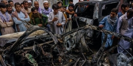 Kerabat dan tetangga dari keluarga Ahmadi berkumpul di kendaraan yang hancur oleh serangan drone AS. 30 Agustus 2021. (Markus Yam/Getty Images) 