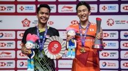 Potret Momota dan Ginting saat naik podium pada ajang BWF World 2019 yang bertempat di China (sumber: bola.com)