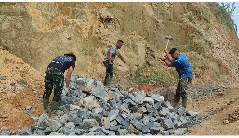 Prajurit TNI Satgas TMMD sedang memecah batu, untuk pengerasan jalan (dokpri)