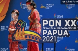 Foto.atara/Adytia Pradana Putra/ Dua warga Papua melintas di depan pernik-pernik Pon Papua 2021
