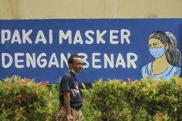 Warga berjalan di depan mural dengan tema COVID-19 di halaman Balai Kota Depok, Depok, Jawa Barat, Rabu (6/1/2021).| Sumber: ANTARA FOTO/Asprilla Dwi Adha/aww.