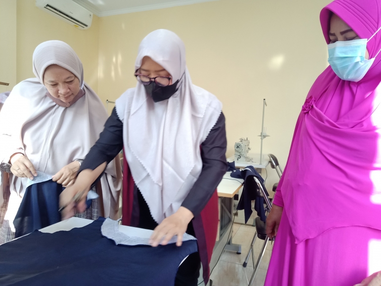 memindahkan pola ke atas kain lalu digunting (dokumen pribadi)