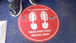 Pesan untuk menjaga jarak tertera di lantai kabin TEMAN Bus/Dokpri.