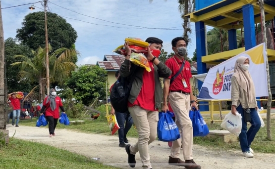 Para relawan dan masyarakat bergotong royong memindahkan paket sembako Founder's Day dari Bidak ke lokasi acara./dokpri