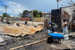 Orang orang bersihkan puing-puing sebuah rumah setelah kerusuhan di Honiara. | Sumber: Evan Wasuka/ABC News
