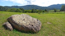 Salah satu batu dakon dengan lubang-lubang yang tampak tak beraturan, dalam area Situs Megalitik  Tadulako di Lembah Behoa, Sulawesi Tengah. (@Hanom Bashari) 