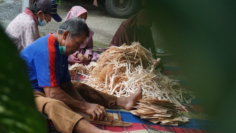 Seorang warga sedang memotong limbah kayu lapis menjadi stik es krim (Foto: Lilian Kiki Triwulan)