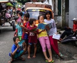 Anak-anak yang sedang membaca buku di perpusatakaan keliling di bemo milik Pak Sutino | Foto diambil dari Kompas/Garry Lotulung