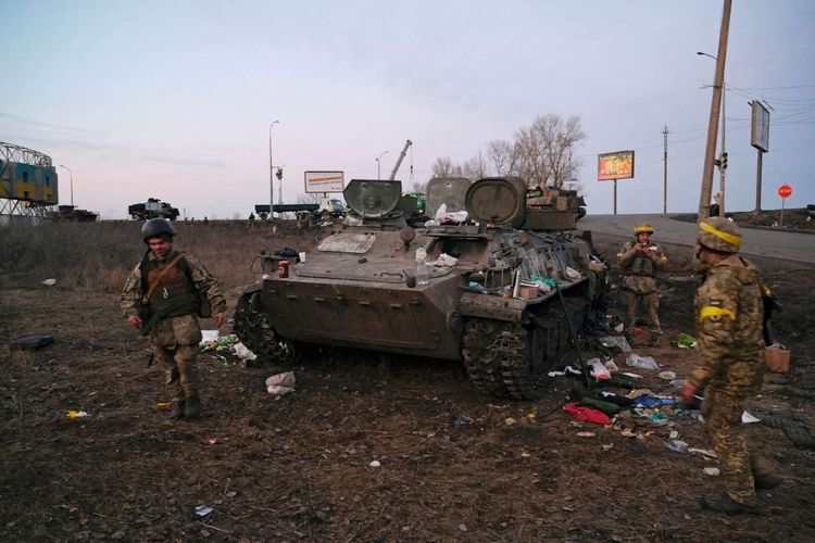 Tentara Ukraina terlihat di samping kendaraan lapis baja yang hancur, yang menurut mereka milik tentara Rusia, di luar Kharkiv, Ukraina, Kamis (24/2/2022). Foto: MAKSIM LEVIN/ANTARA FOTO/REUTERS via KOMPAS.com