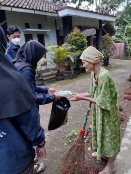 Potret mahasiswi saat membagikan hand sanitizer dan masker pada Mbah Parinah selaku warga Ngroto.
