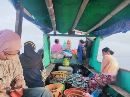 Penumpang yang berada di perahu sembari membawa ikan hasil tangkapan suaminya untuk dijual ke pasar ikan Tanjung luar, foto: Citra Maulida