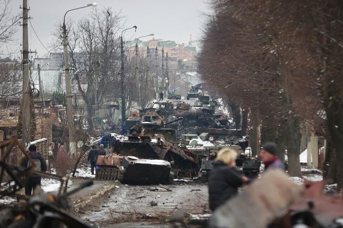 Orang-orang melihat sisa-sisa kendaraan militer Rusia yang hancur di jalan di kota Bucha, dekat ibu kota Kiev, Ukraina, Selasa (1/3/2022). (AP PHOTO/SERHII NUZHNENKO) 