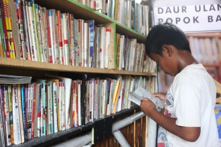 Seorang anak sedang serius membaca buku di Saung Baca Cianjur, Jawa Barat yang didirikan mantan cleaning service, Sandi Mulyadi. Foto: Kompas.com/Firman Taufiqurrahman