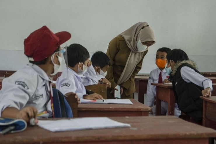Guru mengajarkan murid pada pelaksanaan pembelajaran tatap muka (PTM) 100 persen di SDN 065 Cihampelas, Bandung, Jawa Barat, Senin (10/1/2022). (ANTARA FOTO/NOVRIAN ARBI)