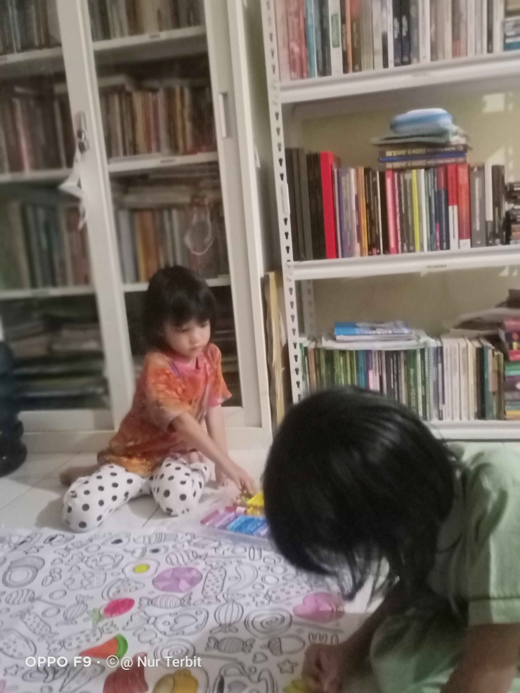 Dua cucu saya Senandung dan Seruni belajar di samping tak buku perpustakaan saya di rumah (foto dok : Nur Terbit)
