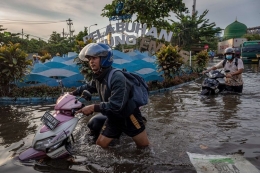 Sejumlah pekerja mendorong motornya yang mogok untuk menerobos banjir limpasan air laut ke daratan atau rob yang merendam kawasan Pelabuhan Tanjung Emas Semarang, Jawa Tengah, Senin (23/5/2022). Foto: Antara Foto/Aji Styawan