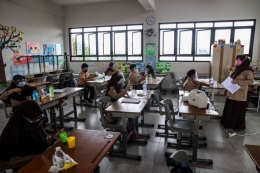 Guru memberikan materi pelajaran kepada murid saat uji coba pembelajaran tatap muka pada hari pertama di SDN 03 Palmerah, Jakarta Barat, Rabu (7/4/2021) (KOMPAS.com/GARRY LOTULUNG)