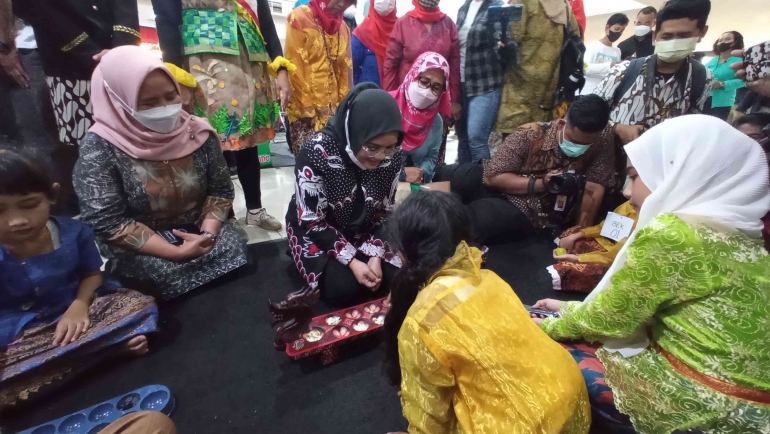 Foto Ibu Rini bersama dengan peserta lomba dakon dalam acara festival nostalgia Surabaya tempo doloe, Kamis (2/6).