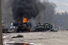Sebuah pengangkut personel lapis baja terbakar dan kendaraan utilitas ringan yang rusak ditinggalkan setelah pertempuran di Kharkiv, Ukraina, Minggu (27/2/2022) (AP PHOTO/MARIENKO ANDREW via KOMPAS.com)