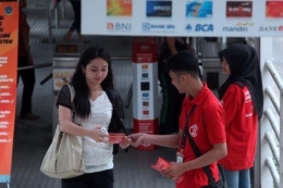 Petugas membagikan brosur E-Tiket Transjakarta kepada penumpang (KOMPAS/WISNU WIDIANTORO)