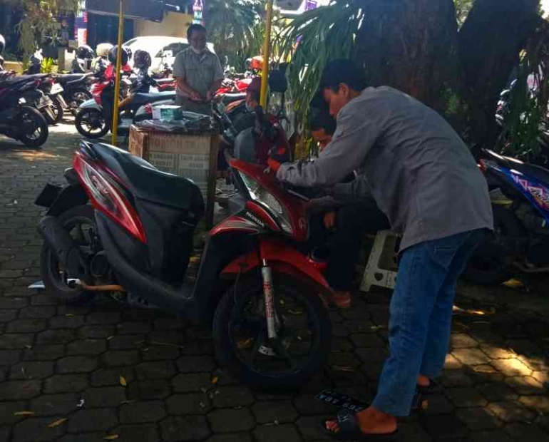 Di depan SAMSAT Malang seorang pemuda melayani pemasangan TNK baru. | Dokumen pribadi.