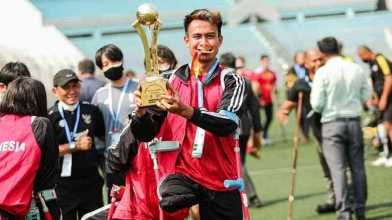 Aditya memamerkan trofi penanda kelolosan timnas Indonesia ke Piala Dunia Amputasi 2022. FOTO: INAF/PSAI via BBC