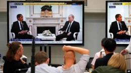 Wartawan menonton di layar TV pertemuan Vladimir Putin dan Presiden Indonesia Joko Widodo di Kremlin di Moskow, 30 Juni 2022.Foto : VOA Indonesia 