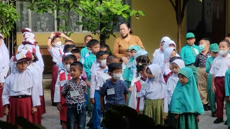 Wali Kelas I menenangkan peserta didik baru yang masih canggung dan menangis saat upacara bendera (Foto: Akbar Pitopang)