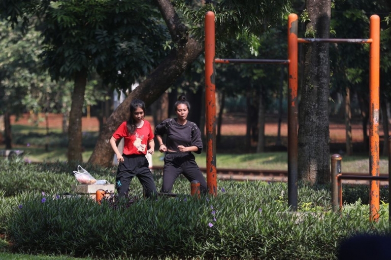 Dua remaja putri berlatih gerakan tari modern sembari berjemur di bawah terik mentari pagi di ruang terbuka hijau di kawasan Tanah Kusir, Jakarta (9/7/2021) (KOMPAS/TOTOK WIJAYANTO)