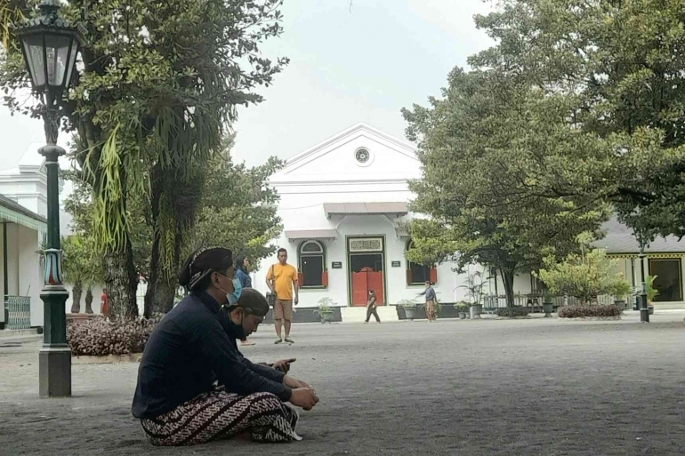 Abdi dalem duduk di pelataran halaman Keraton Yogyakarta. 