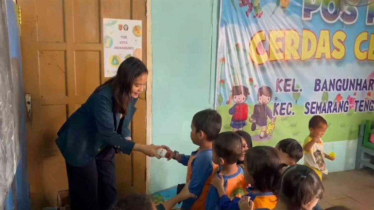 Mahasiswa KKN membagikan susu untuk anak-anak, foto : Dokumentasi Pribadi