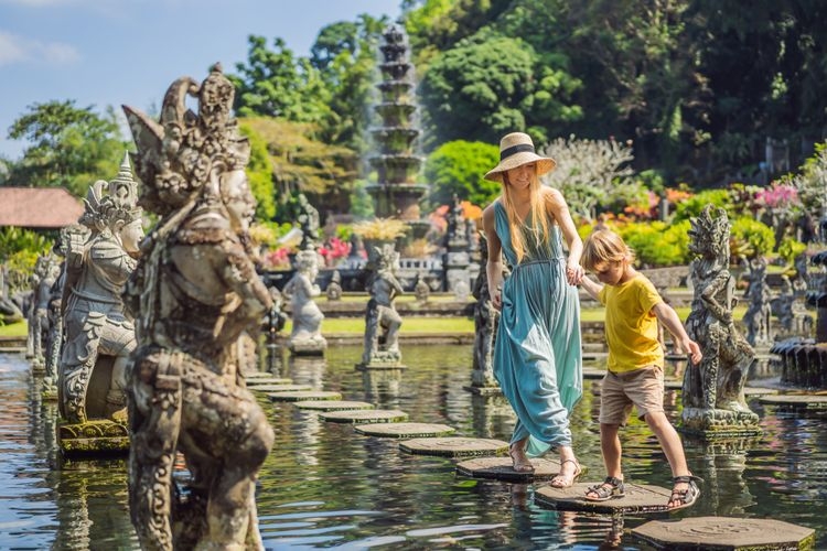 Ilustrasi turis mengunjungi Taman Tirta Gangga, Bali. (sumber: SHUTTERSTOCK/Elizaveta Galitckaia via kompas.com)