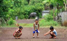 Anak-anak sedang bermain kelereng dilapangan dengan penuh keseriusan | tribunnews.com