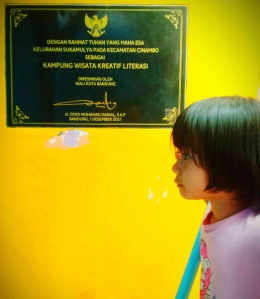 Seorang anak tengah bermain di lokasi Kampung Wisata Kreatif Literasi Kecamatan Cinambo Kota Bandung, berdekatan dengan prasasti peresmiaan kampung wisata. Dokpri