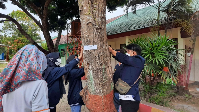 Kelompok 343 memasang papan nama untuk flora di SMPN 1 Pujer