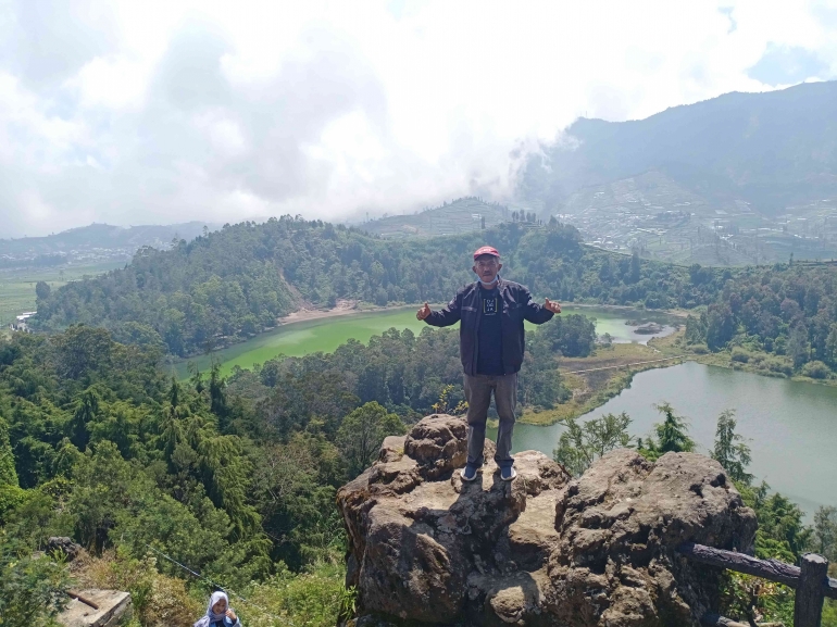Penulis berdiri di Puncak Gunung Ratapan Angin dengan latar belakang Telaga Warna. Sumber: Dokpri