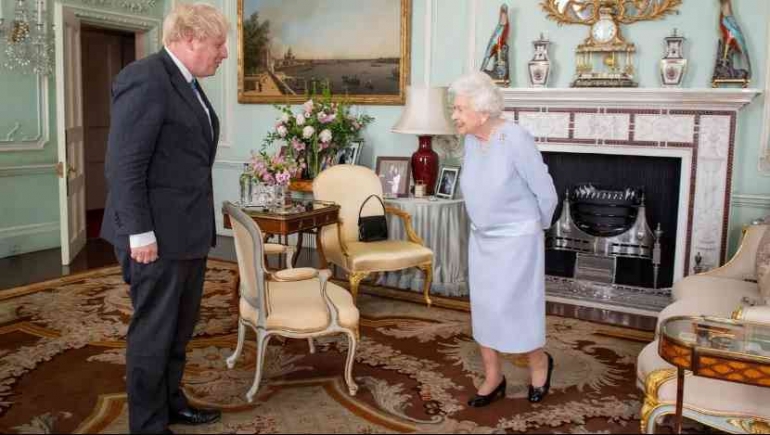 Ratu Elizabeth II menyapa Perdana Menteri Inggris Boris Johnson selama audiensi di Istana Buckingham di London pusat pada 23 Juni 2021. (Dominic Lipinski / POOL / AFP) 