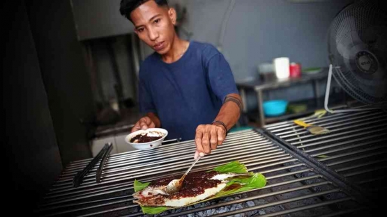 Asisten koki Waroenk Seafood Dony tengah membakar ikan bakar parape. / Foto: Effendy Wongso