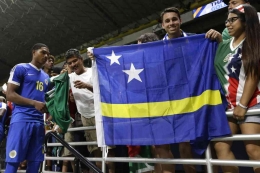 Fans timnas Curacao mengibarkan bendera negaranya di tribun. FOTO: Twitter/CuracaoFootball