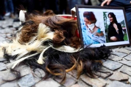 Aksi memotong rambut sebagai  protes kematian Mahsa Amini, di Gerbang Brandenburg di Berlin, Jerman, 23 September 2022. Foto: Christian Mang. REUTERS
