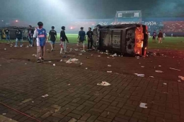 Mobil K-9 dibalik oleh supporter Aremania dalam kericuhan yang terjadi di Stadion Kanjuruhan, Sabtu (1/10/2022).(KOMPAS.COM/Imron Hakiki)