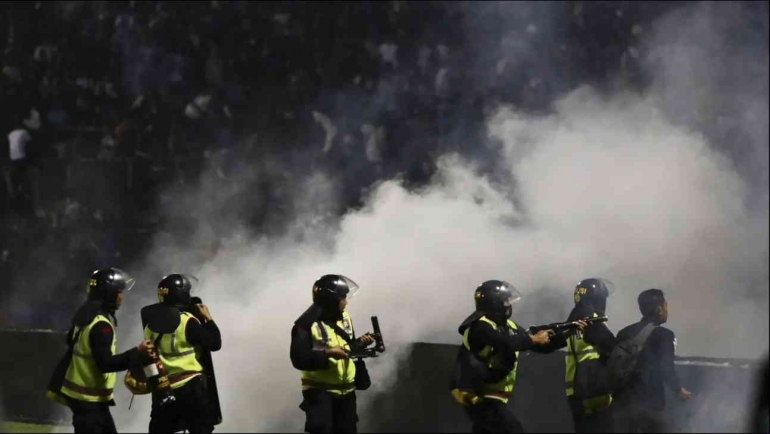 Pihak keamanan yang melontarkan gas air mata. Sumber: Bola.com