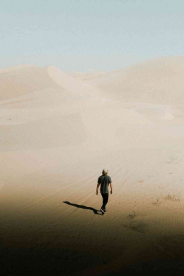 Seorang laki-laki sedang berjalan di padang gurun. Sumber: Pexels / Ethan Jones