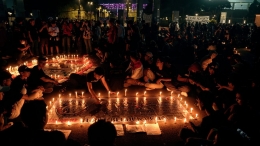 Pencinta sepak bola melakukan tabur bunga, menyalakan 1.000 lilin, dan berdoa bersama untk menghormati kawan-kawan Aremania yang menjadi korban Tragedi Kanjuruhan di pintu masuk Asia Afrika, Stadion Gelora Bung Karno, Jakarta, Minggu (2/10/2022) malam. (KOMPAS/AGUS SUSANTO)