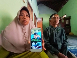 Nurul Kharimah (kiri) dan Hadi Mabtuhin menunjukkan potret Muhammad Mungizul, korban Tragedi Kanjuruhan - Dok. Moch. Luki Azhari/Radar Blitar.
