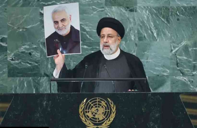 Presiden Iran Ebrahim Raisi mengangkat foto untuk memperingati kemartiran Soleimani. (kredit foto: BRENDAN MCDERMID/REUTERS)