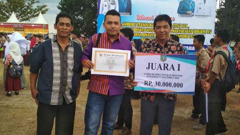 Manajer BUMDes Arih Ersada dan Kepala Desa Raya menerima penghargaan sebagai BUMDes Terbaik I Tingkat Provinsi Sumatera Utara, 2019 (Dok. Pribadi)